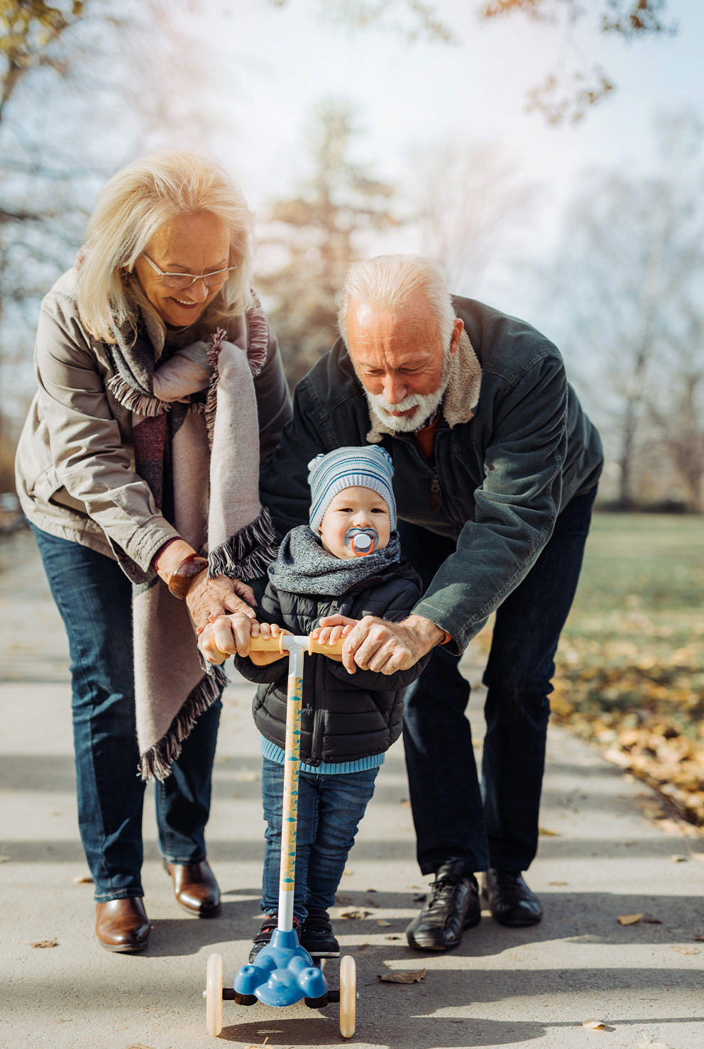happy retired couple walking and playing with their grandson at the park